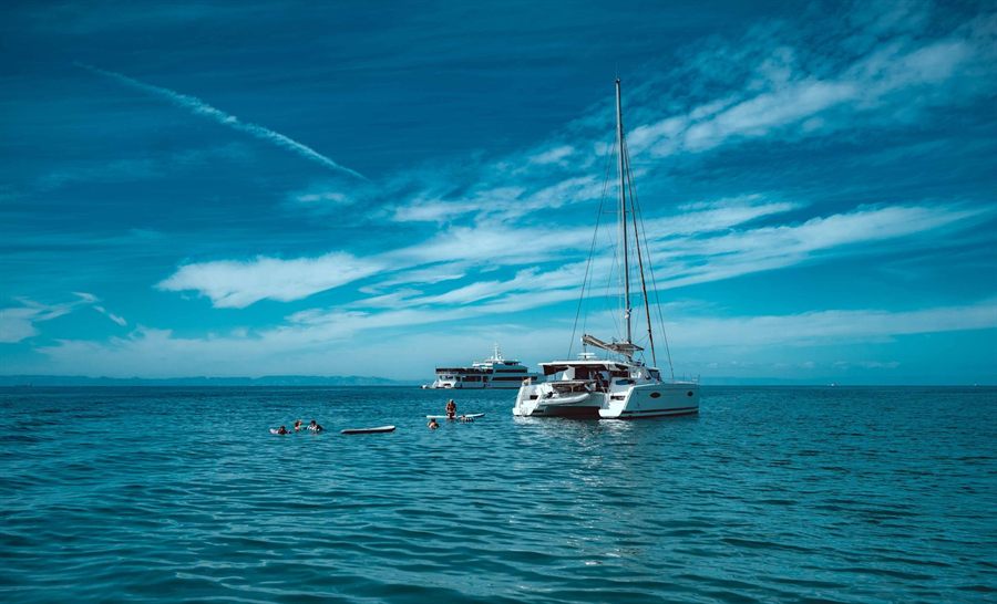 Catamaran moored in open water with snorkelers swimming nearby
