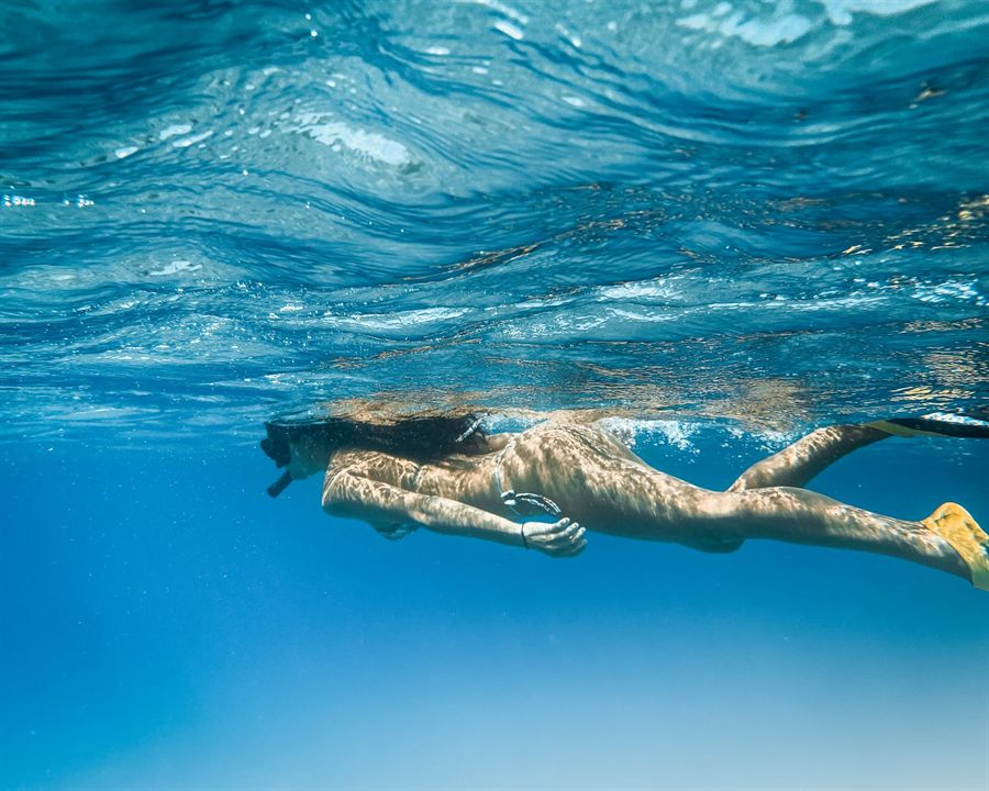 Snorkeler floating face-down in clear blue Hawaiian water