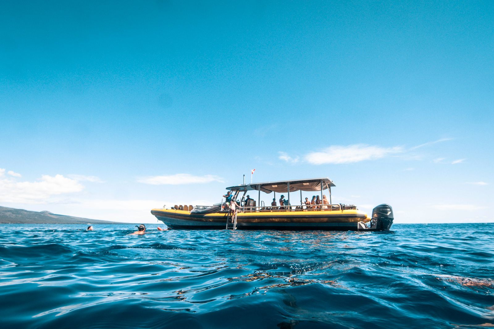 Snorkel boat with passengers on calm blue water off Maui, the way every Molokini crater snorkeling trip begins